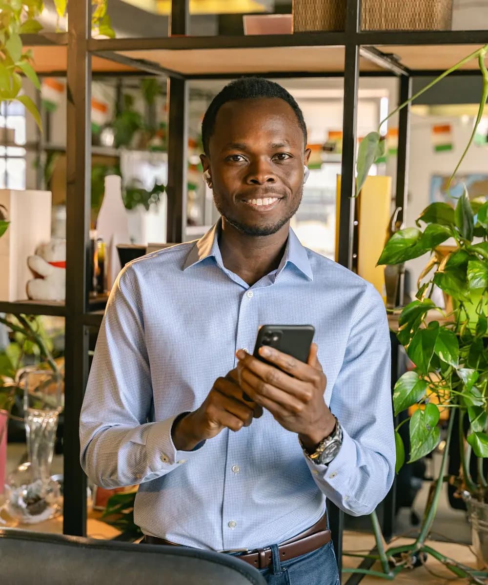 Un jeune responsable souriant consulte son téléphone dans ses locaux